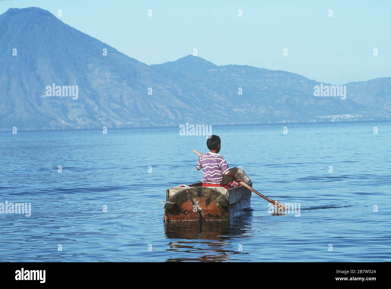 Guatemala, America Centrale: Bambini file piccola barca sul lago Atitlan con vulcani incombenti sullo sfondo. ©Bob Daemmrich Foto Stock