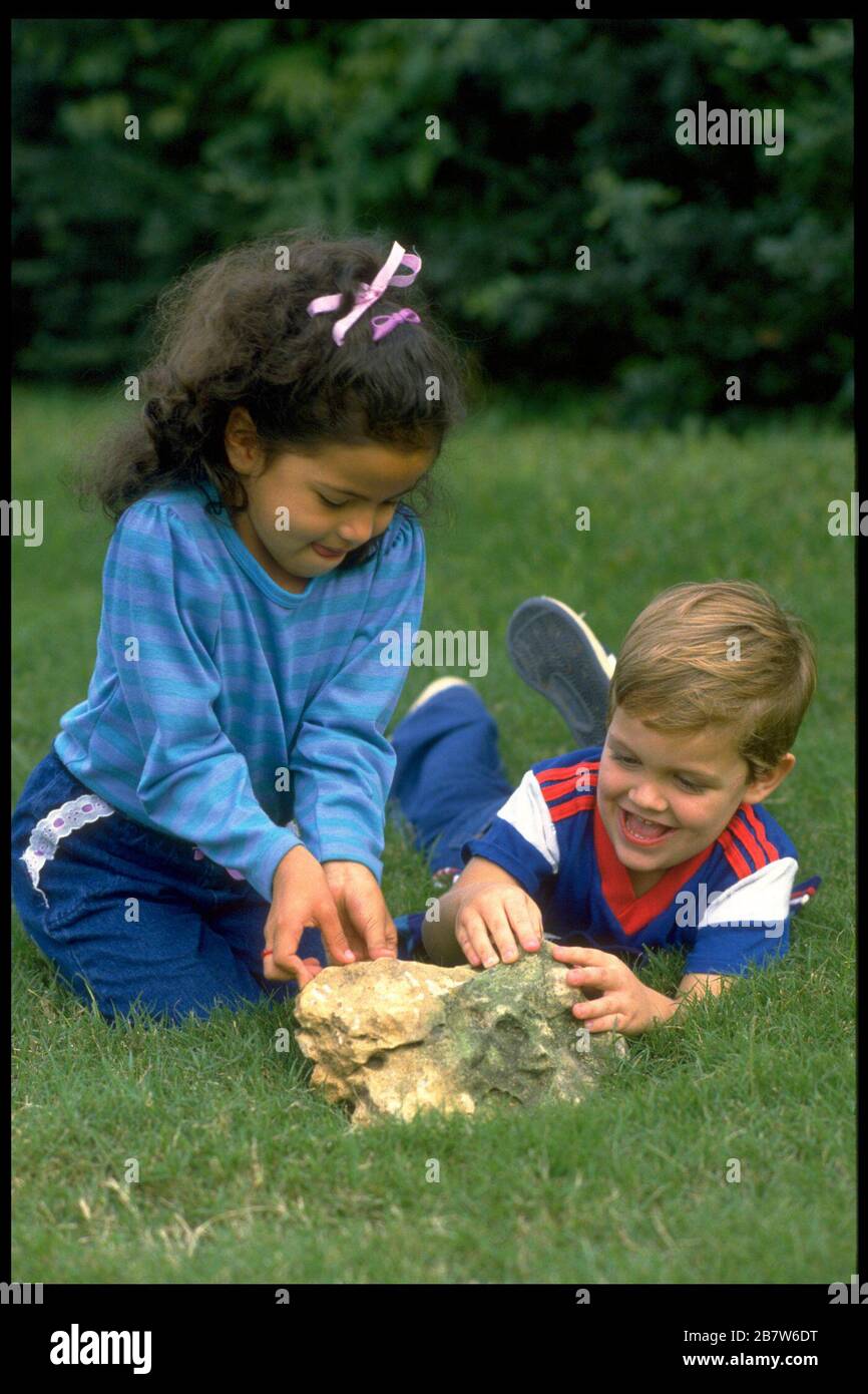 Bambina e ragazzo di quattro anni ispezionano la colonia di formiche sotto la roccia nel parco. SIGNOR ©Bob Daemmrich Foto Stock