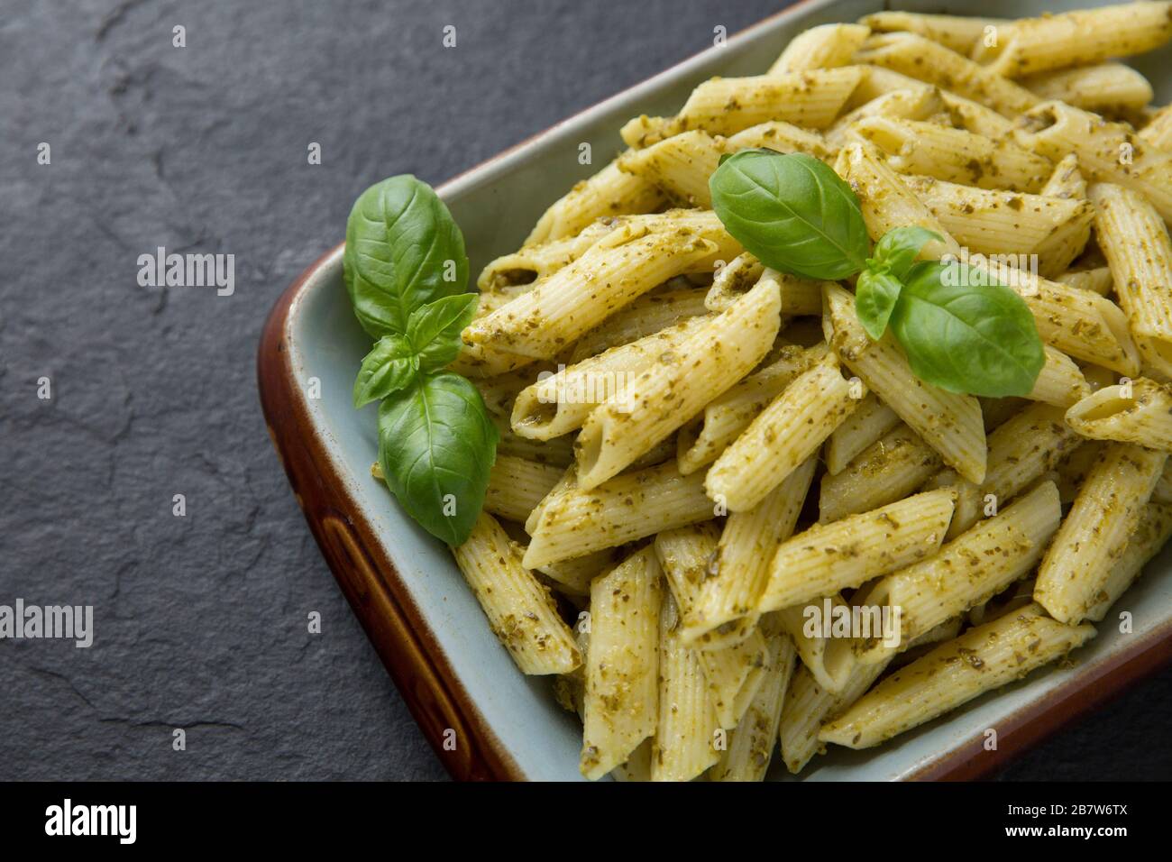 Un pasto a pranzo di Penne con pesto verde guarnito con foglie di basilico. Inghilterra GB Foto Stock