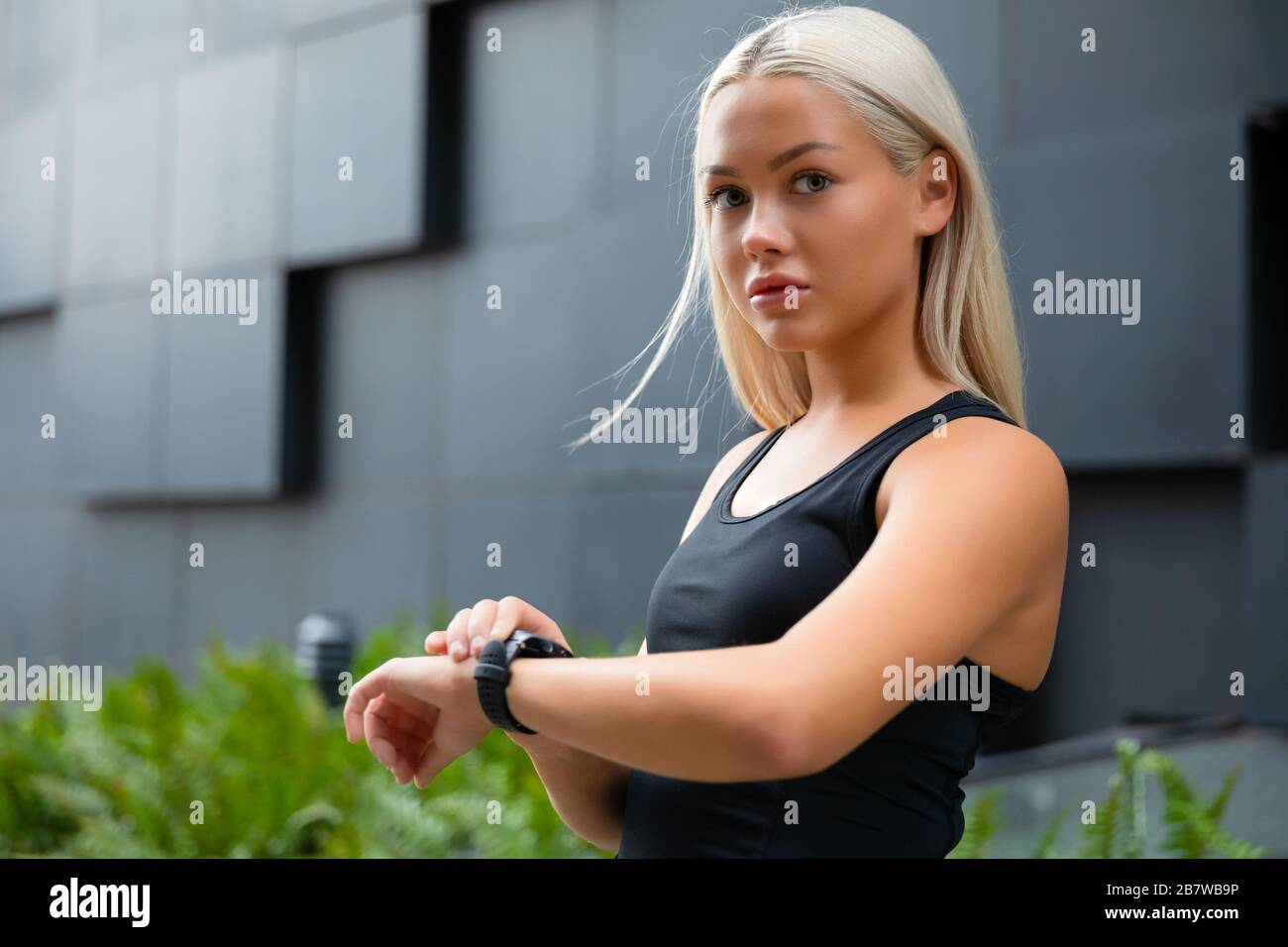 Giovane donna bionda che controlla il suo dispositivo smart watch fitness in città Foto Stock