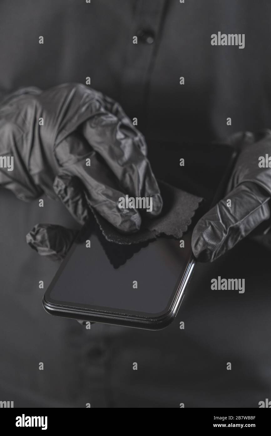 Pulizia dello schermo dello smartphone con un panno. Tutto nero concetto, igiene personale e virus o prevenzione di diffusione di infezioni Foto Stock
