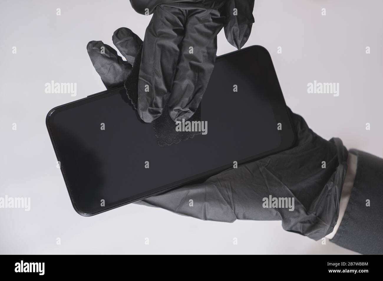 Pulizia dello schermo dello smartphone con un panno. Tutto nero concetto, igiene personale e virus o prevenzione di diffusione di infezioni Foto Stock