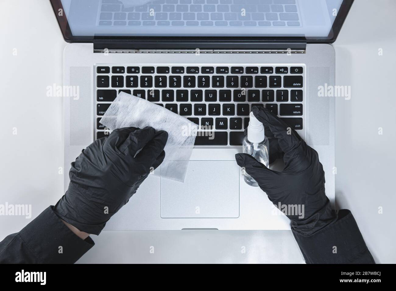 Pulizia della tastiera del notebook con un igienizzatore, vista dall'alto. Concetto di igiene e prevenzione della diffusione dei virus sul lavoro o a casa Foto Stock