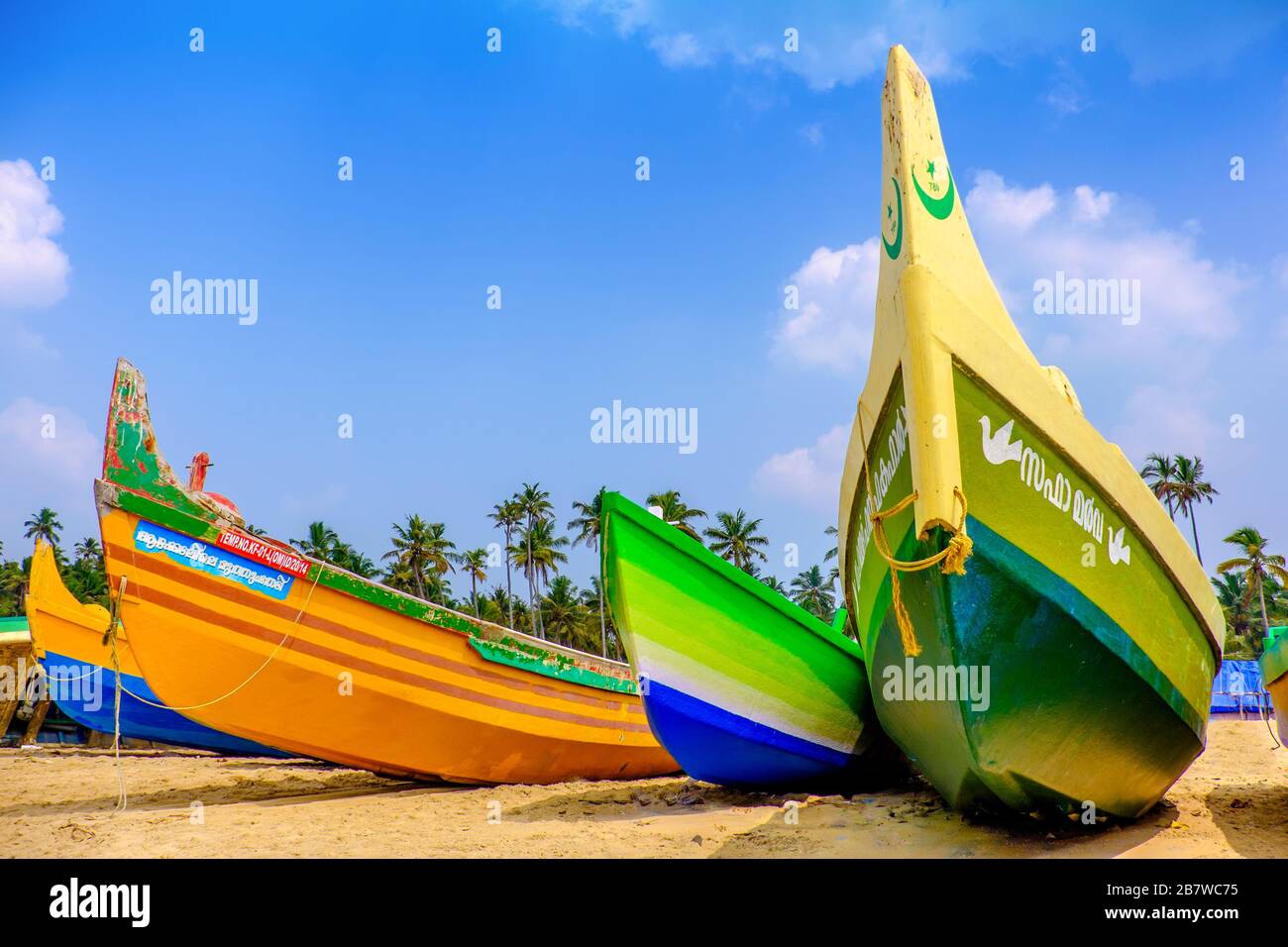 Barche da pesca dipinte con colori vivaci su una spiaggia sulla costa indiana Foto Stock