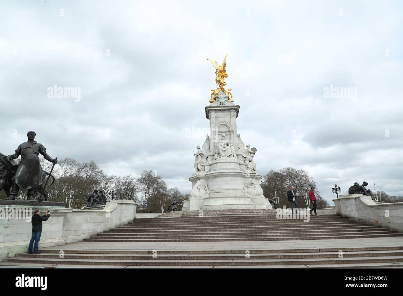 Tre persone al Queen Victoria Memorial di fronte a Buckingham Palace a Londra, mentre il numero di vittime del coronavirus nel Regno Unito ha raggiunto 71 persone. Foto Stock