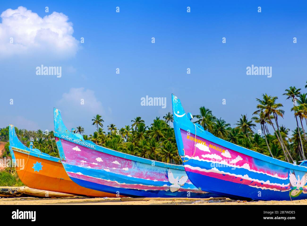 Barche da pesca dipinte con colori vivaci su una spiaggia sulla costa indiana Foto Stock