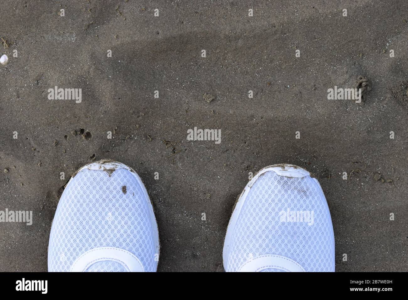 Scarpe da ginnastica bianche che camminano sulla sabbia vista dall'alto, scarpe da running che camminano sulla sabbia Foto Stock