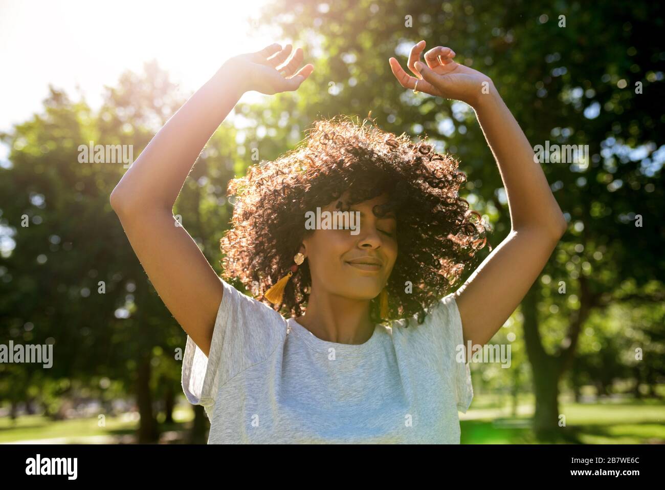 Giovane donna che balla in un parco in un pomeriggio soleggiato Foto Stock