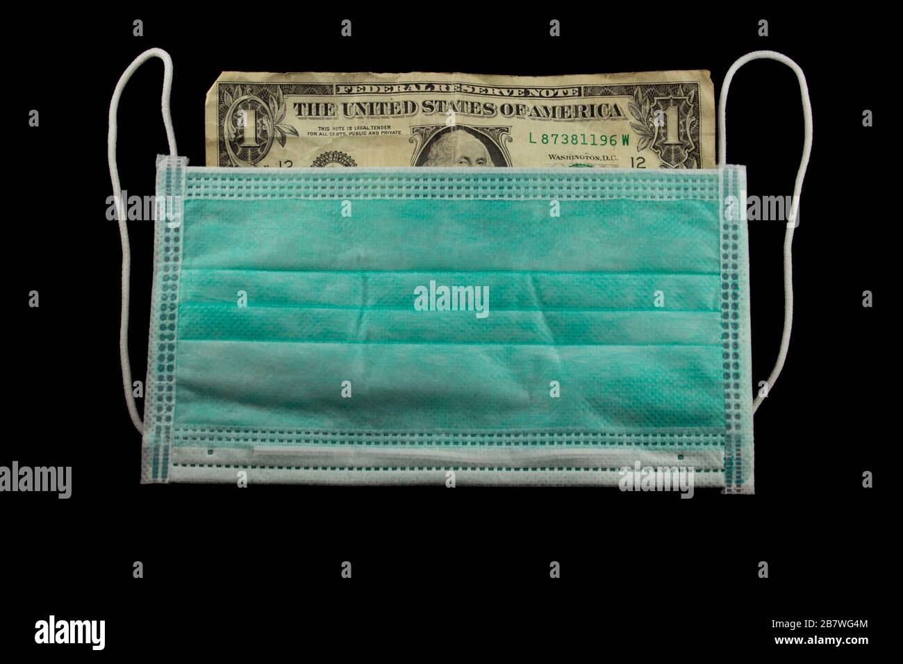 Carta del dollaro rugosa dietro una maschera medica del viso Foto Stock