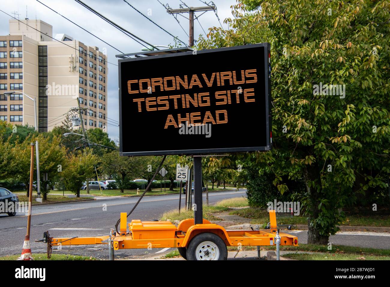 Segnale stradale digitale da una strada suburbana che dice Coronavirus Testing Site ahead Foto Stock