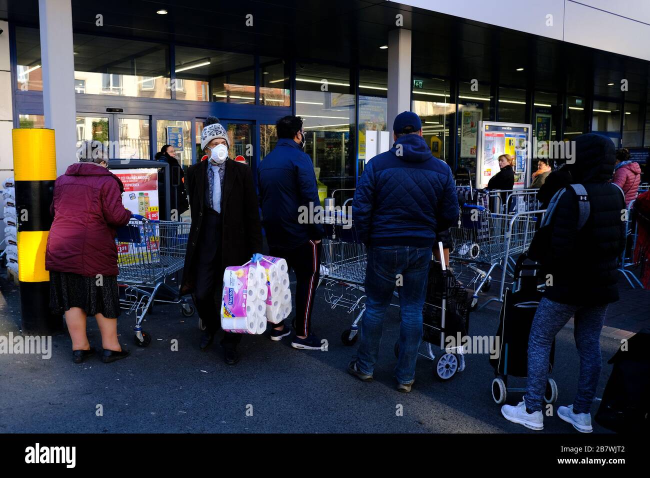 Bruxelles, Belgio. 18 Marzo 2020. Gli acquirenti si trovano in coda al di fuori di un supermercato prima che il governo belga imponga un blocco di coronavirus. Credit: ALEXANDROS MICHAILIDIS/Alamy Live News Foto Stock