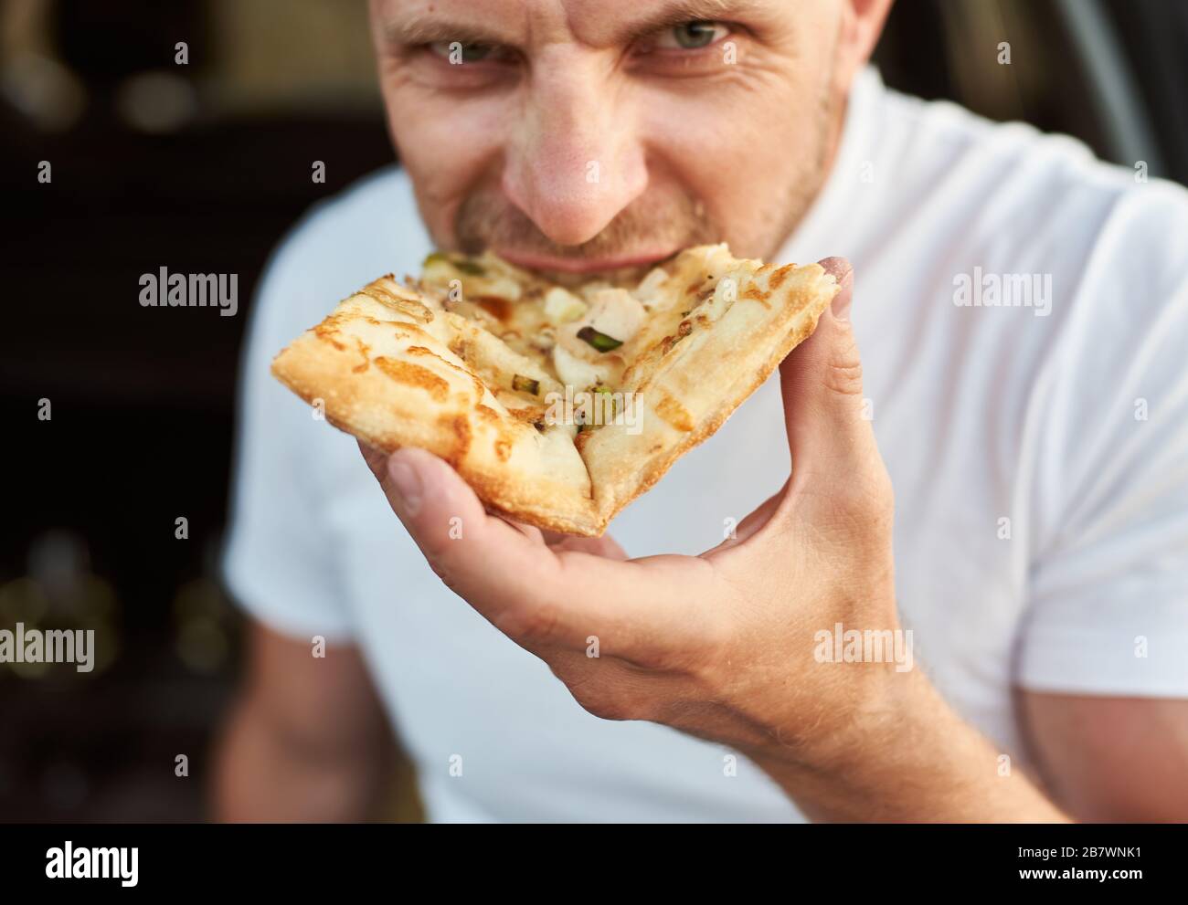 Vista ravvicinata dell'uomo affamato che mangia un pezzo di pizza Foto Stock