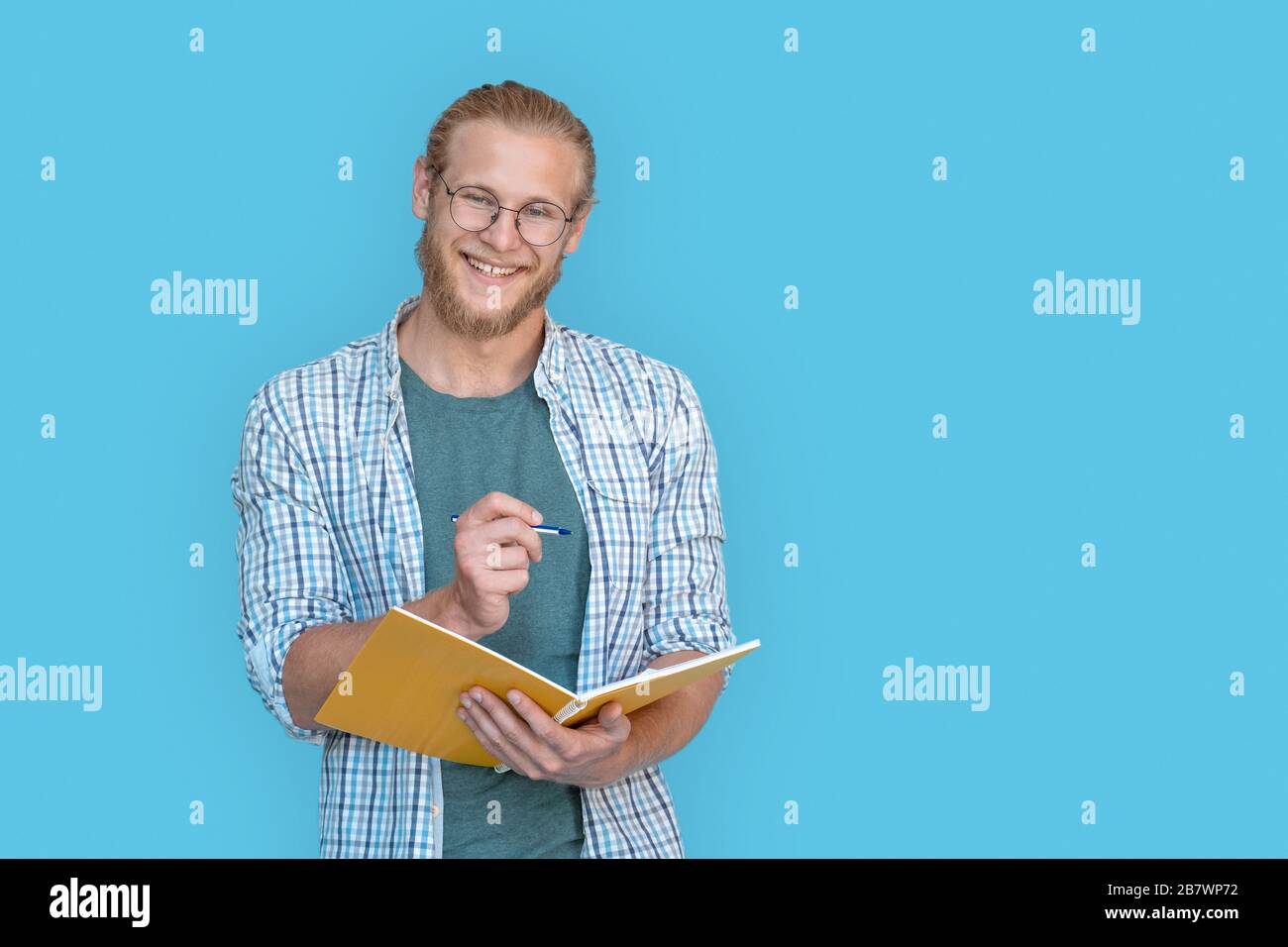 Happy man studente tenere scrivere in notebook isolato su sfondo blu, ritratto. Foto Stock