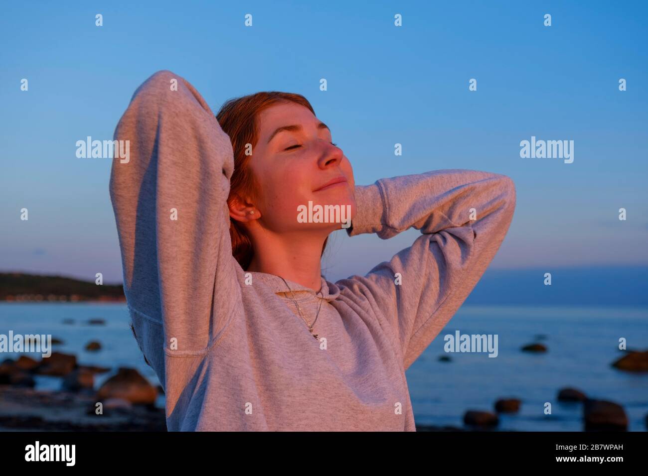 Ragazza, giovane donna che gode il tramonto sulla costa, Kattegat, riserva naturale di Saerdess, vicino Haverdalsstrand, Hallands Laen, Svezia meridionale, Svezia Foto Stock