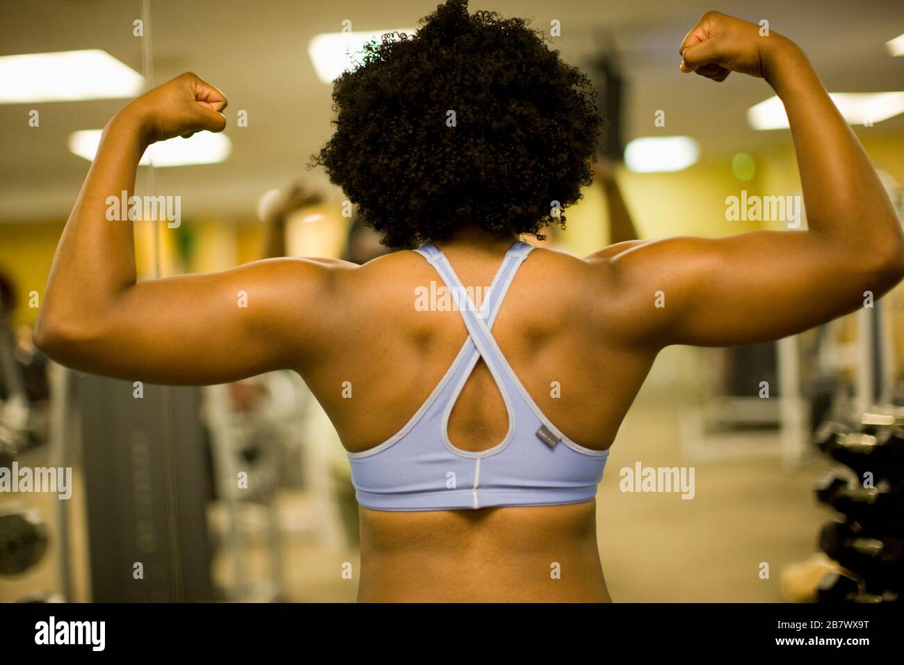 Giovane donna flettendo i suoi muscoli in una palestra a. Foto Stock