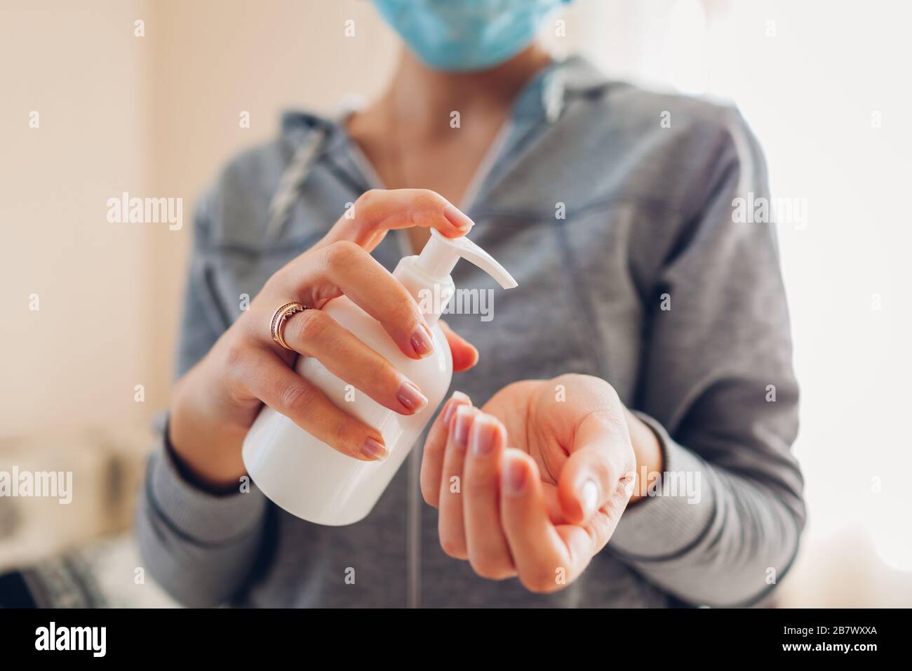 Virus Corona covid-19. Donna lava le mani con gel di alcol sapone antibatterico igienizzante indossa maschera medica. Assistenza sanitaria Foto Stock