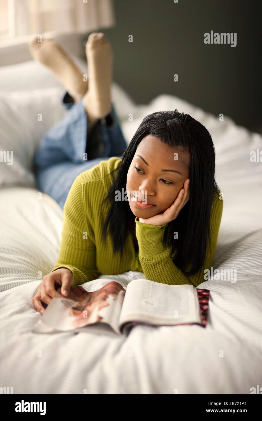 Ragazza adolescente giacente sul suo letto giorno sogno durante la lettura di una rivista. Foto Stock