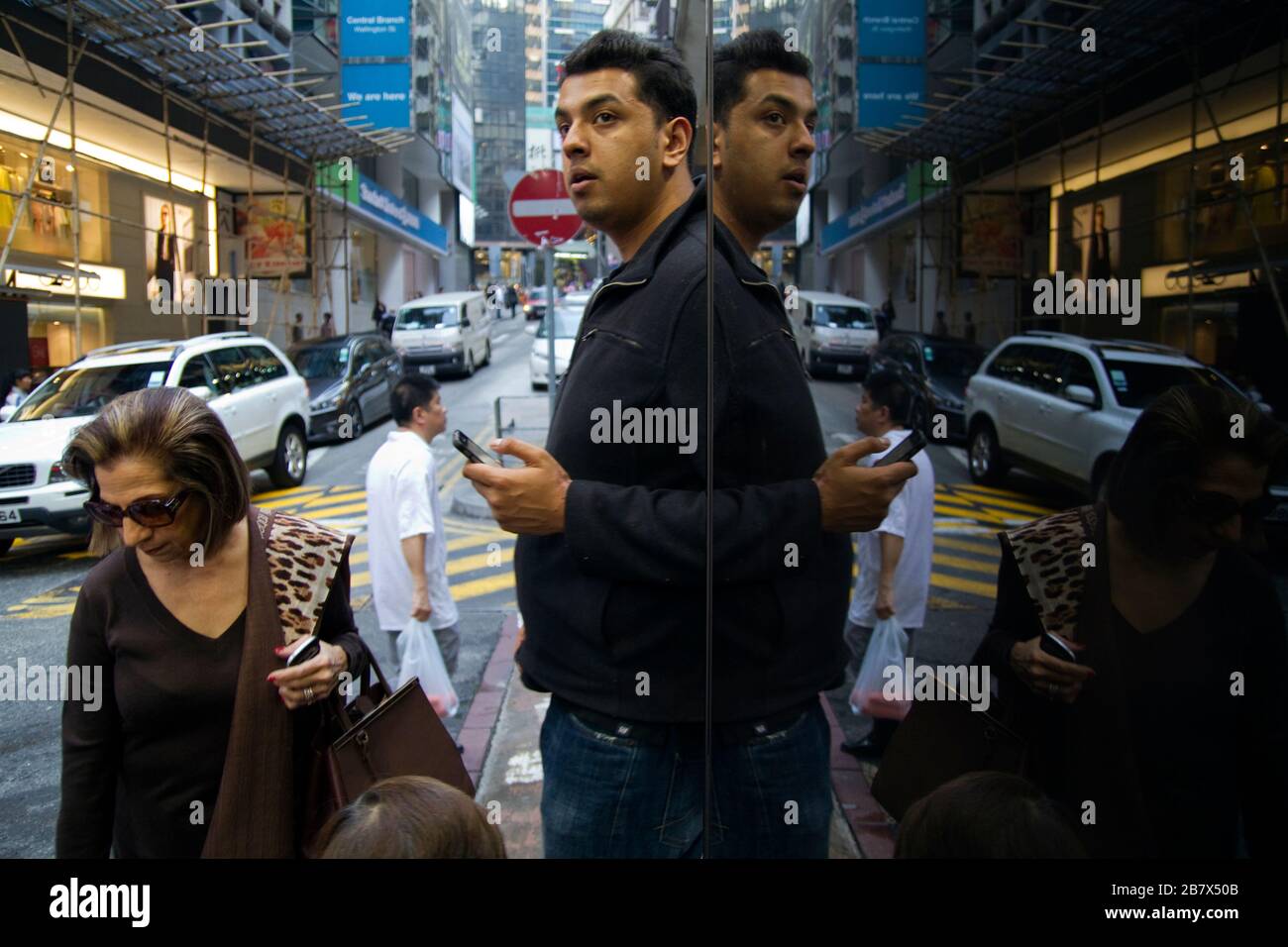 Uomo e donna in via Hong Kong si sono riflessi nella finestra a specchio, la scena della strada Foto Stock