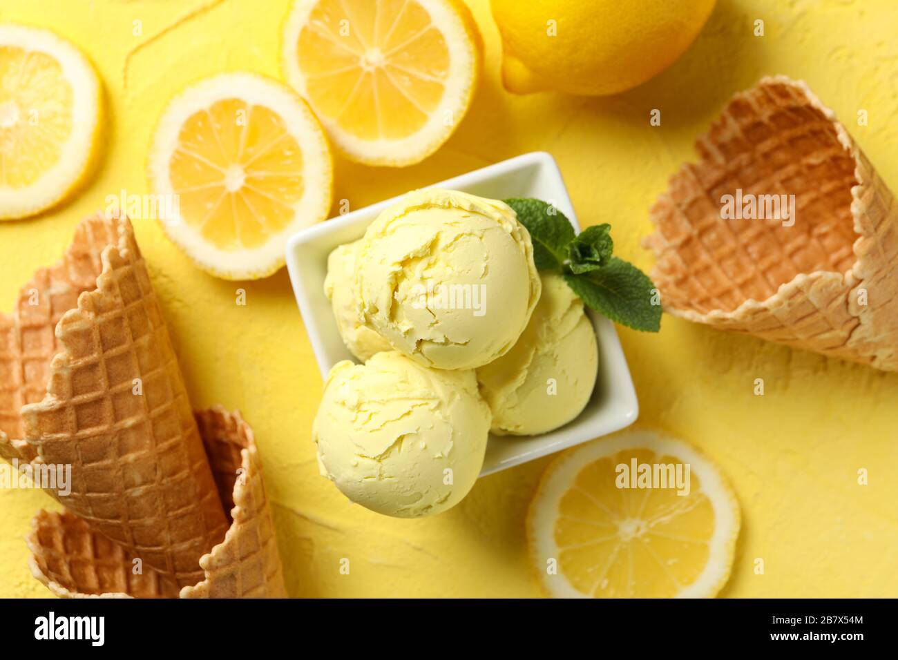 Gelato, limone e waffle su sfondo giallo, vista dall'alto Foto Stock