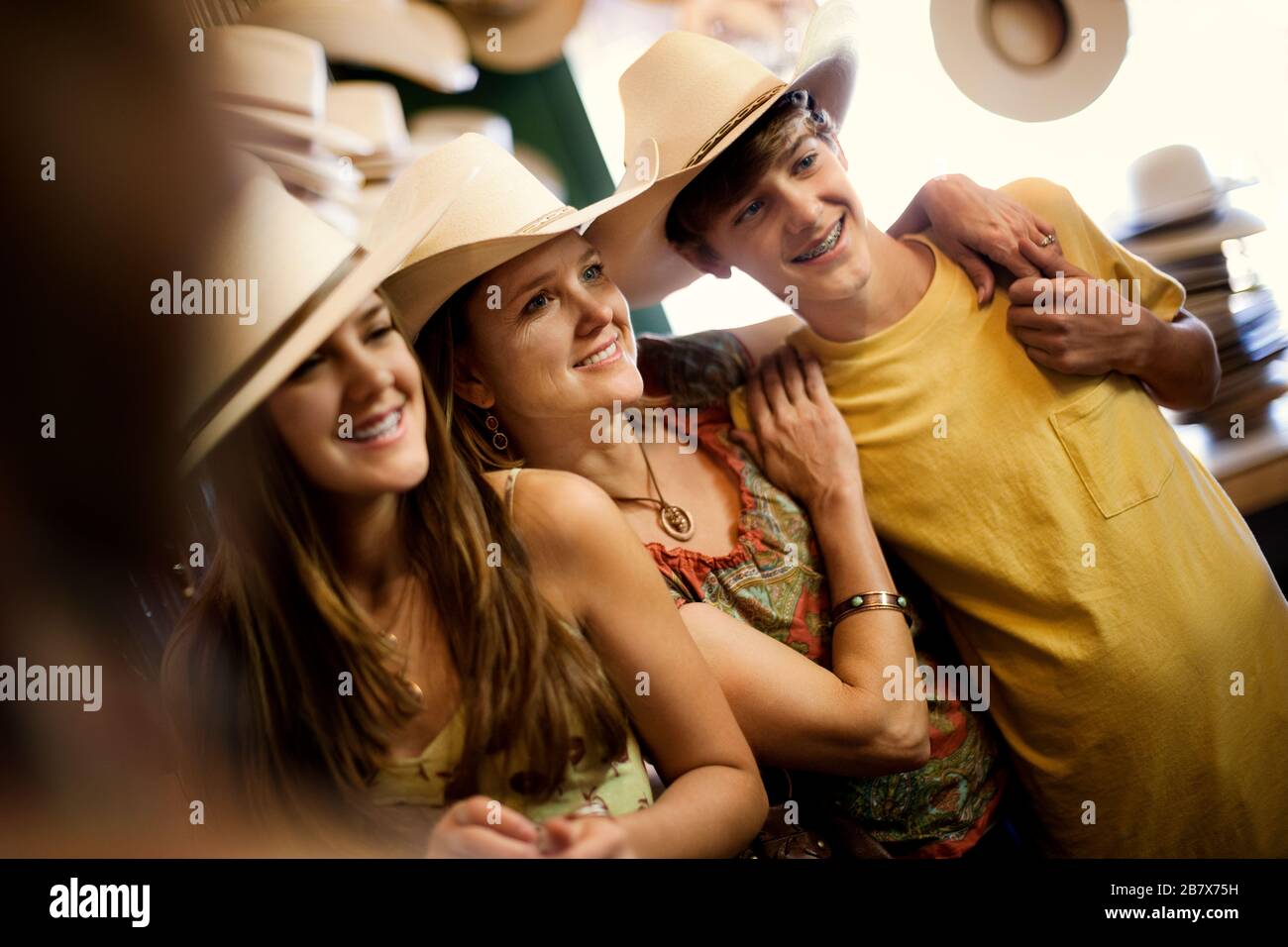 Sorridente madre e figli adolescenti cercando sui cappelli da cowboy. Foto Stock