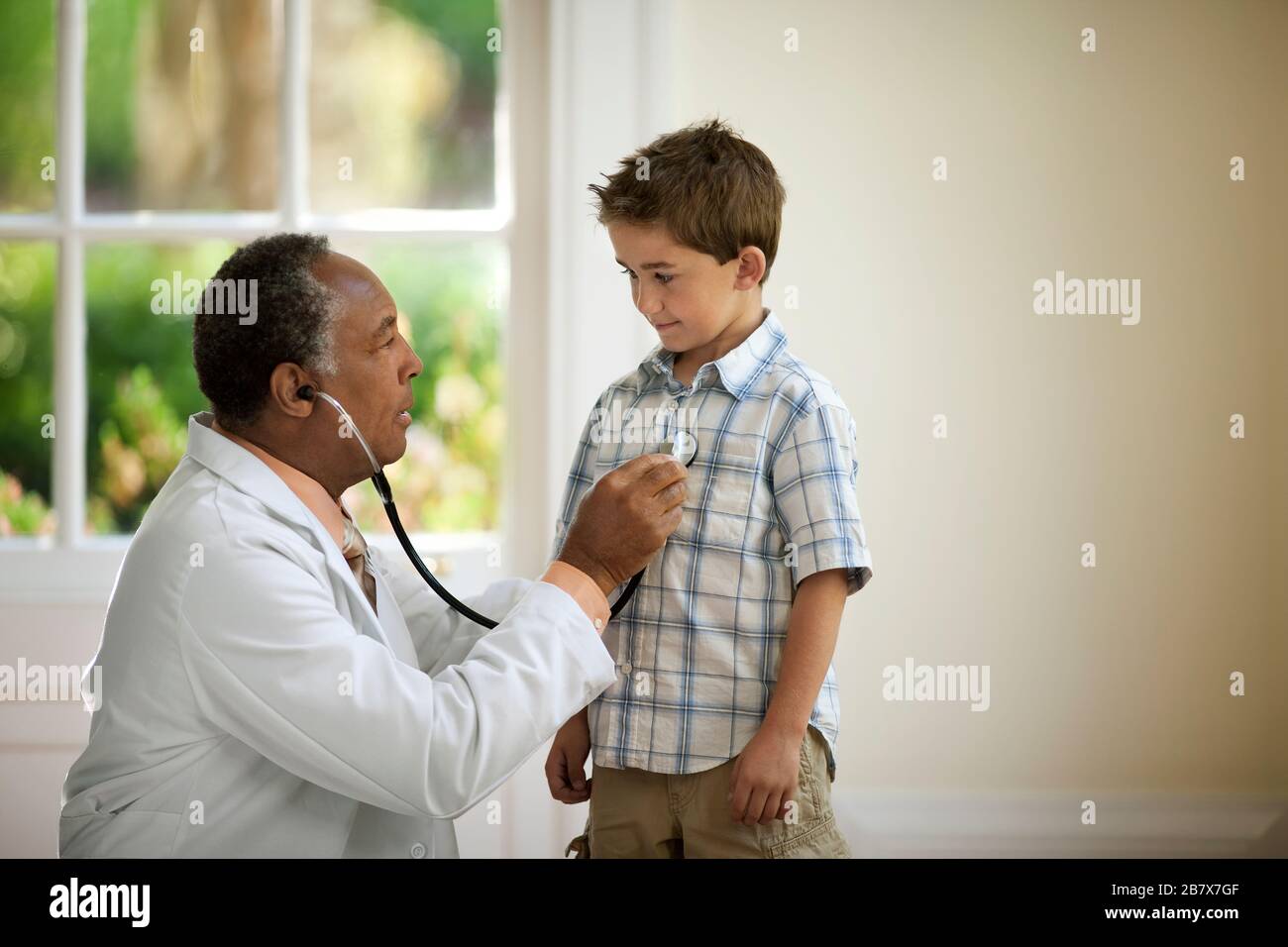 Medico senior che ascolta il battito cardiaco di un giovane paziente con uno stetoscopio. Foto Stock