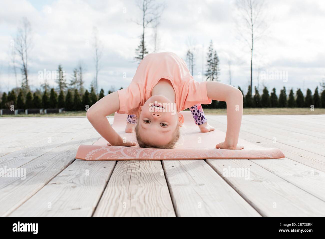 giovane ragazza che fa ginnastica e yoga nel suo cortile posteriore a casa Foto Stock