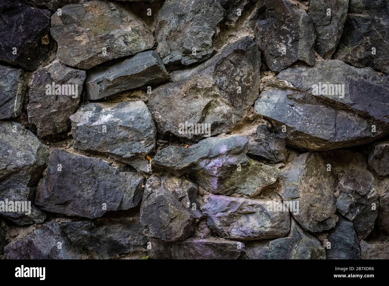 Parte del muro di pietra, per sfondo e texture. Pietra naturale tagliata ruvida Foto Stock