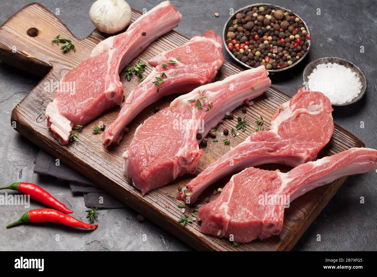 Costolette di agnello in cucina. Stinco di agnello crudo con spezie e condimenti Foto Stock