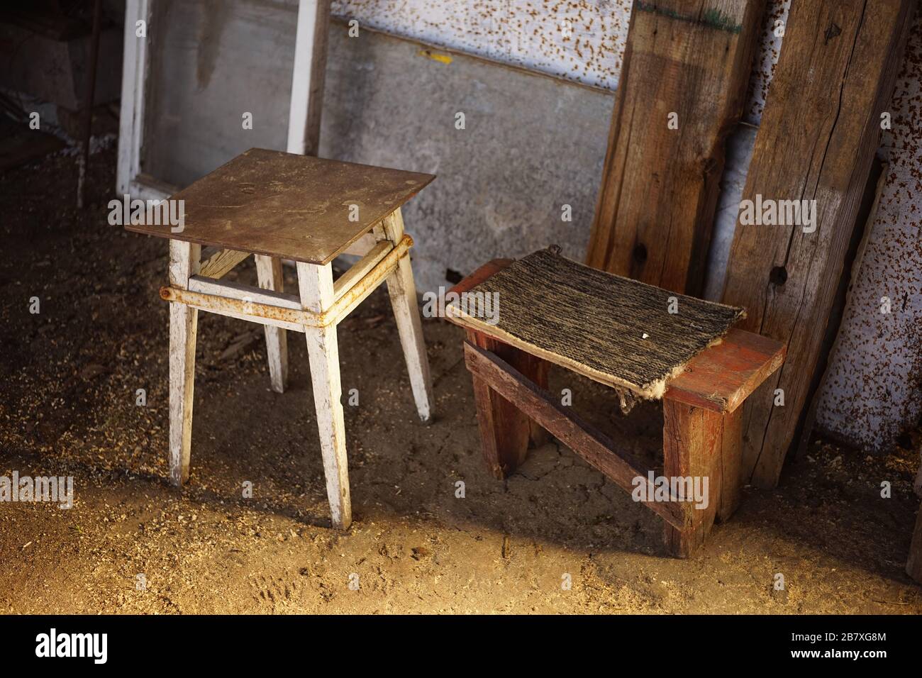 Due vecchia sedia di legno bassa in un cortile rurale sul terreno. Foto Stock