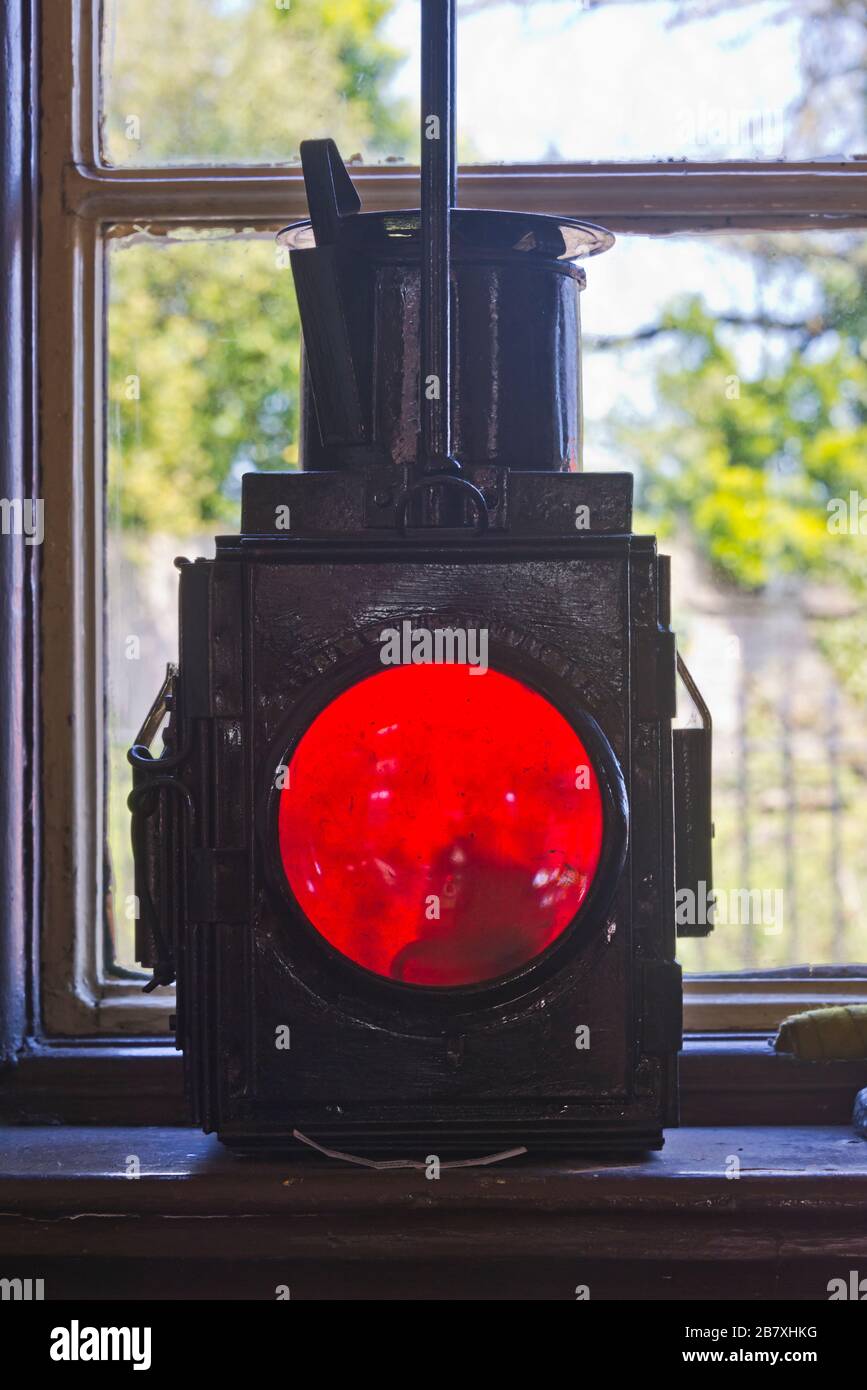Una lanterna di avvertimento rossa su una soglia di vento della sala d'attesa alla stazione ferroviaria di Cranmore sulla East Somerset Railway Foto Stock