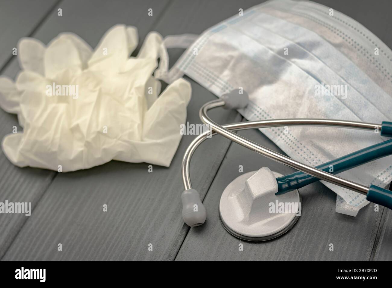 Maschera facciale, guanti in lattice e stetoscopio su sfondo di legno grigio Foto Stock