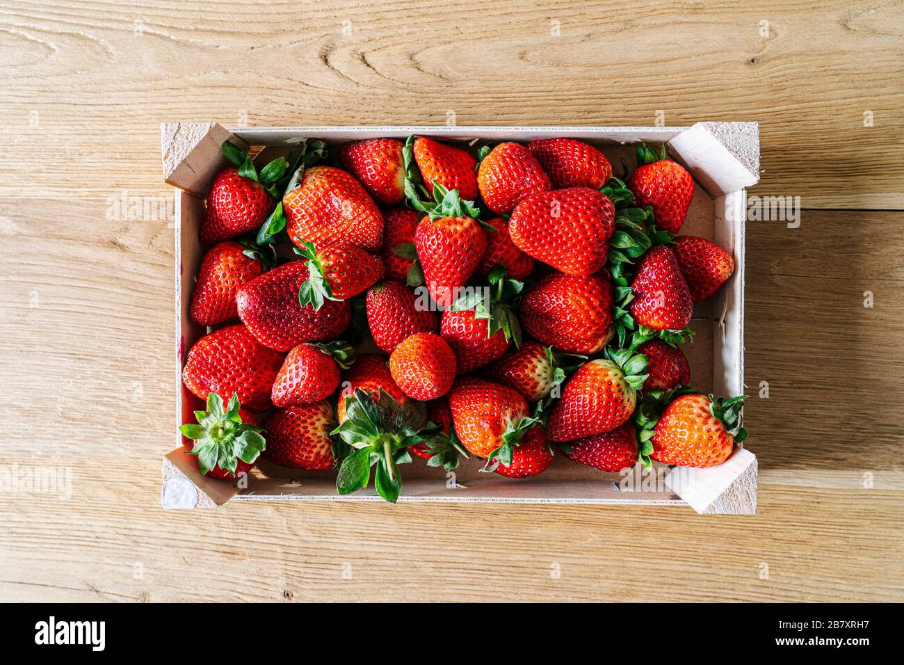 Una scatola di frutta ripiena di fragole vista dall'alto su un tavolo di legno Foto Stock