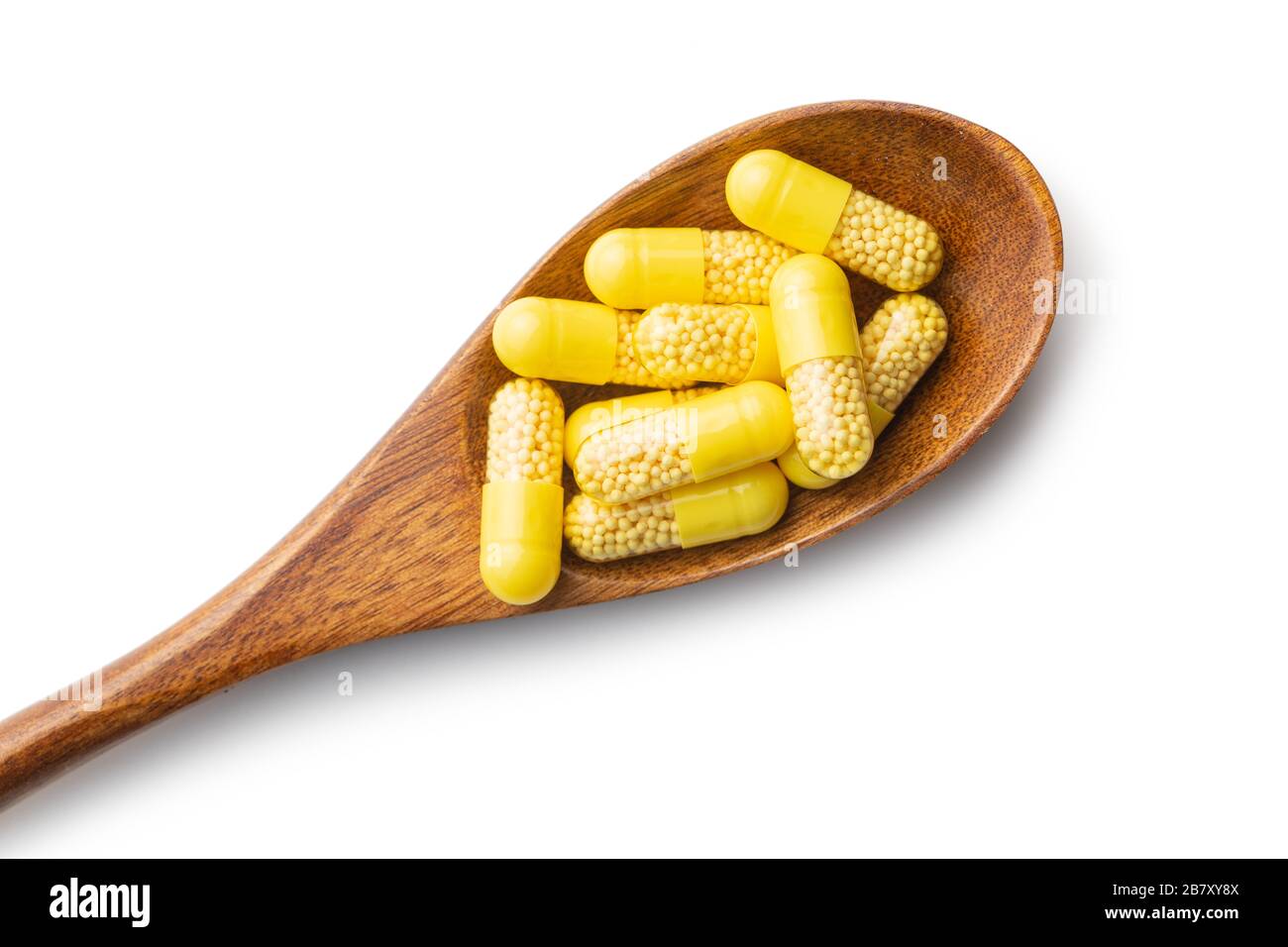 Capsule vitaminiche in cucchiaio di legno. Pillole di vitamina C isolate su sfondo bianco. Foto Stock