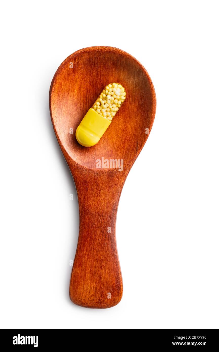 Capsule vitaminiche in cucchiaio di legno. Pillole di vitamina C isolate su sfondo bianco. Foto Stock
