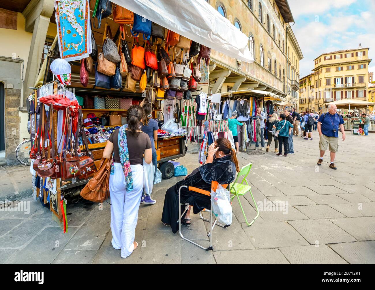 Una turista donna acquista souvenir da un piccolo negozio di articoli in pelle e abbigliamento in Piazza Santa Croce a Firenze Foto Stock