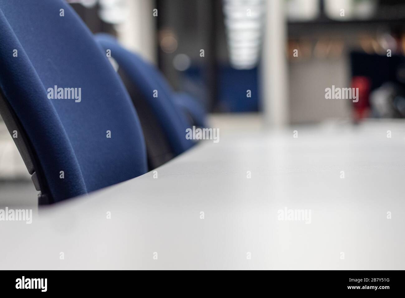 Le sedie sono allineate su una lunga scrivania in uno spazio co-ufficio. Foto Stock