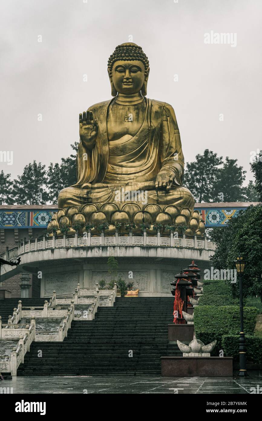 Chongqing, Cina - 20 dicembre 2019: Le persone con umbrealla ammirano la statua dorata di Budda durante la pioggia nel Tempio di Hua Yan a Chongqing, Cina sudoccidentale Foto Stock