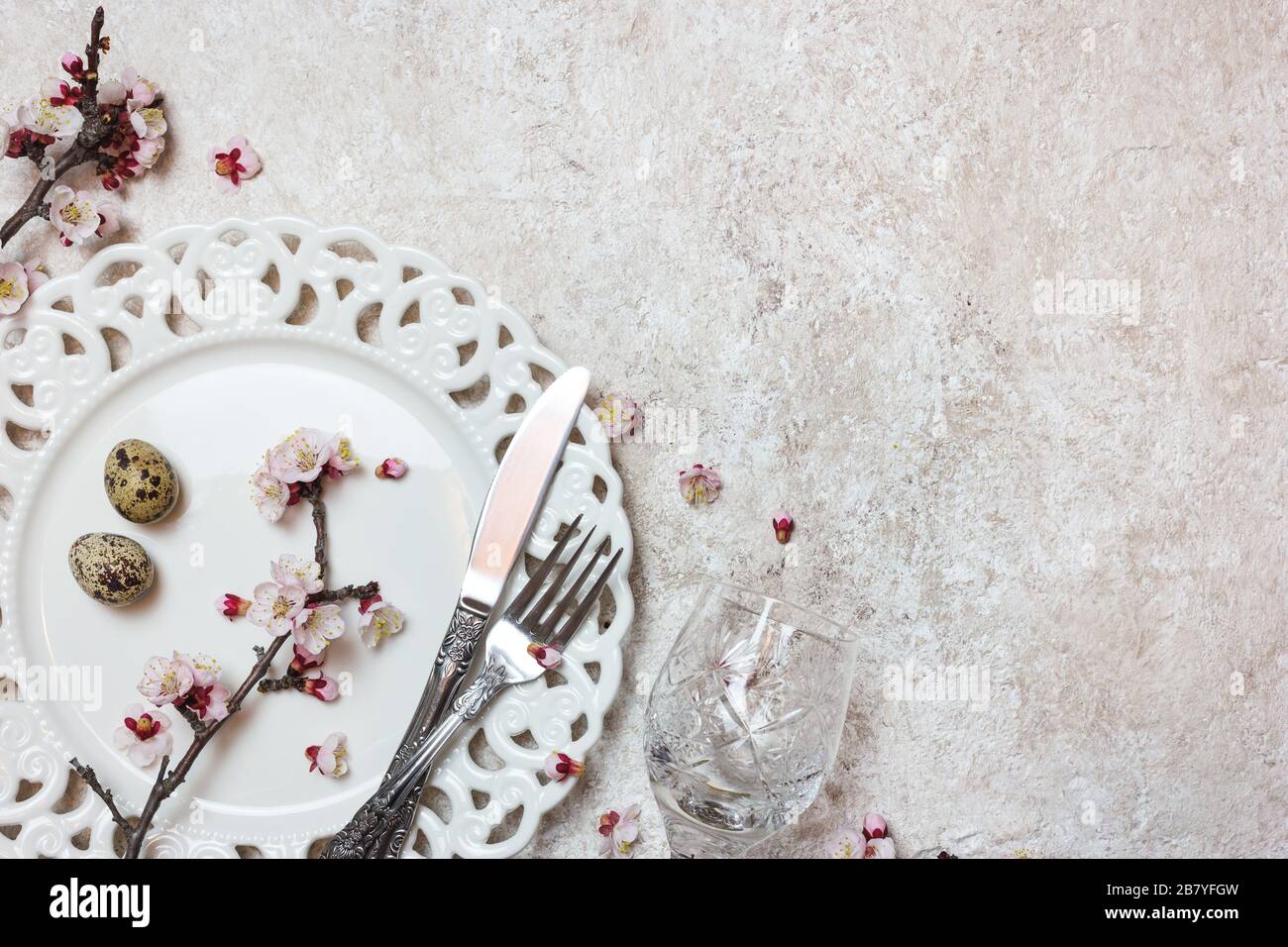 Bella tavola di festa con ramificazioni primavera fiore su sfondo chiaro textured. Vista dall'alto con spazio di copia. Foto Stock