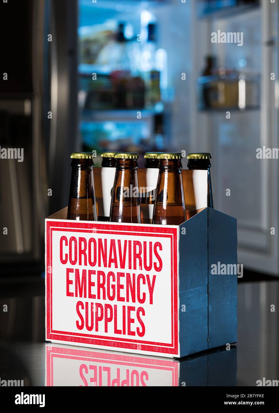 Confezione da sei bottiglie di birra marrone nella scatola con i materiali di consumo di emergenza Coronavirus stampigliati sul lato. Frigorifero freddo fuori fuoco sul retro. Vista umorante dell'accaparramento Foto Stock