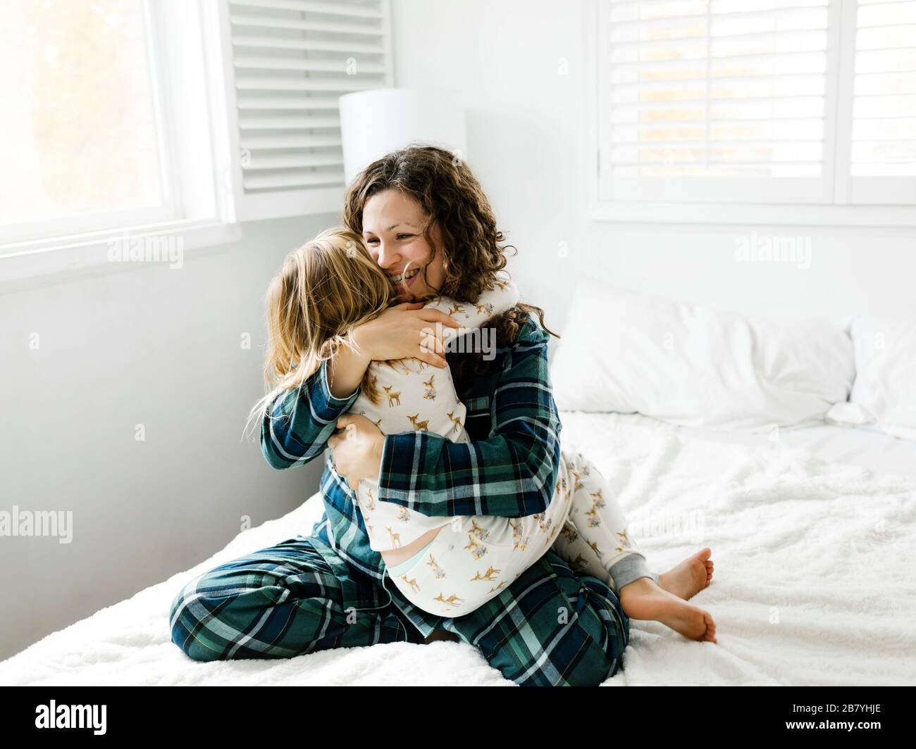 Madre e figlia abbracciando sul letto Foto Stock