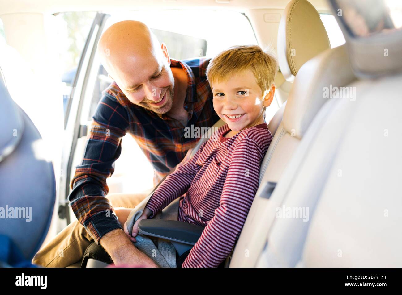 Ragazzo sorridendo mentre suo padre allacciava la cintura di sicurezza Foto Stock