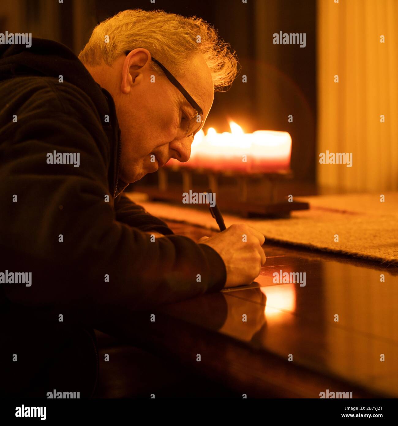 Uomo anziano che scrive la lettera a lume di candela Foto Stock