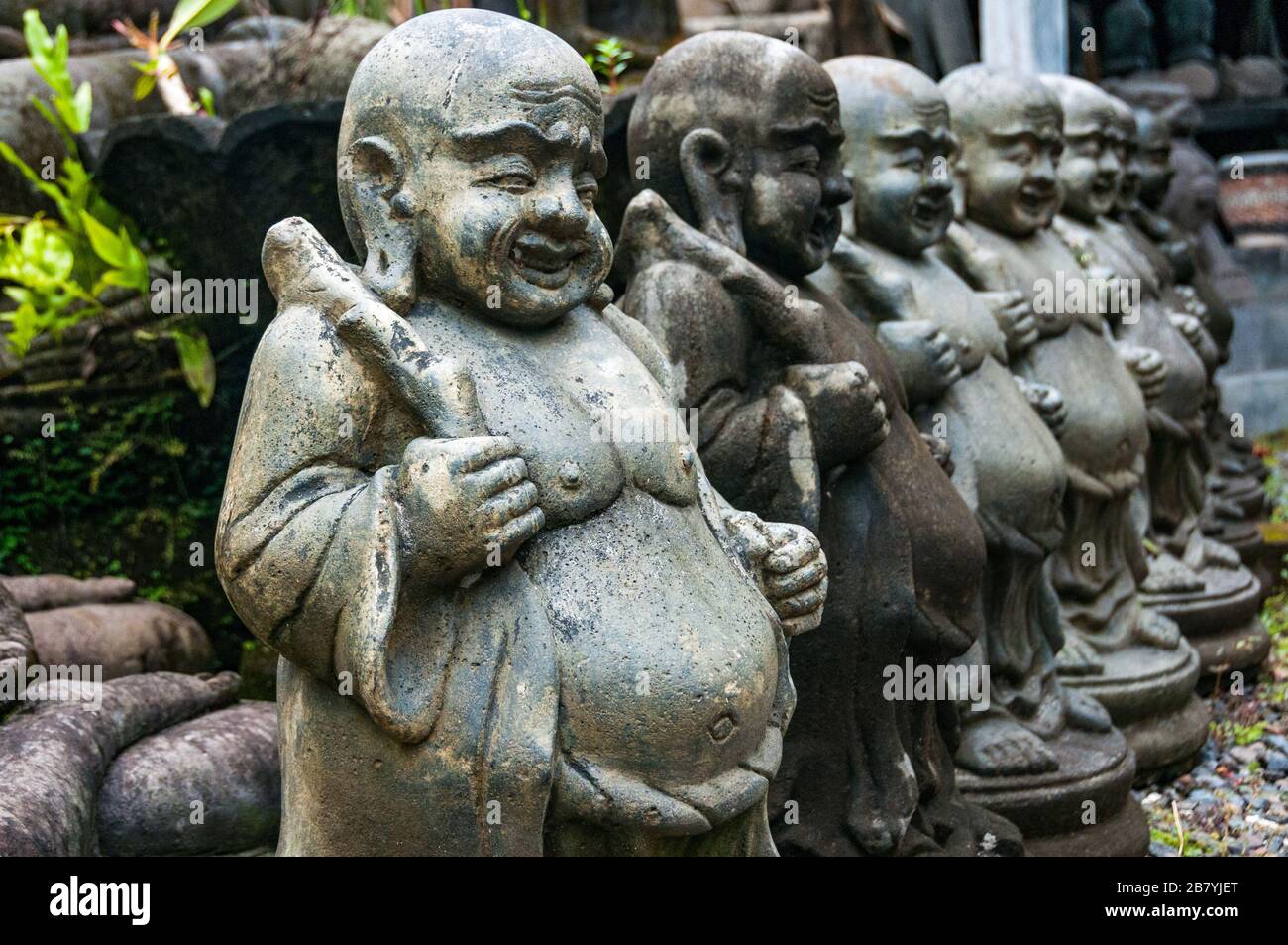 Una fila di statue monaci grasse in una fabbrica di sculture a Bali. Foto Stock