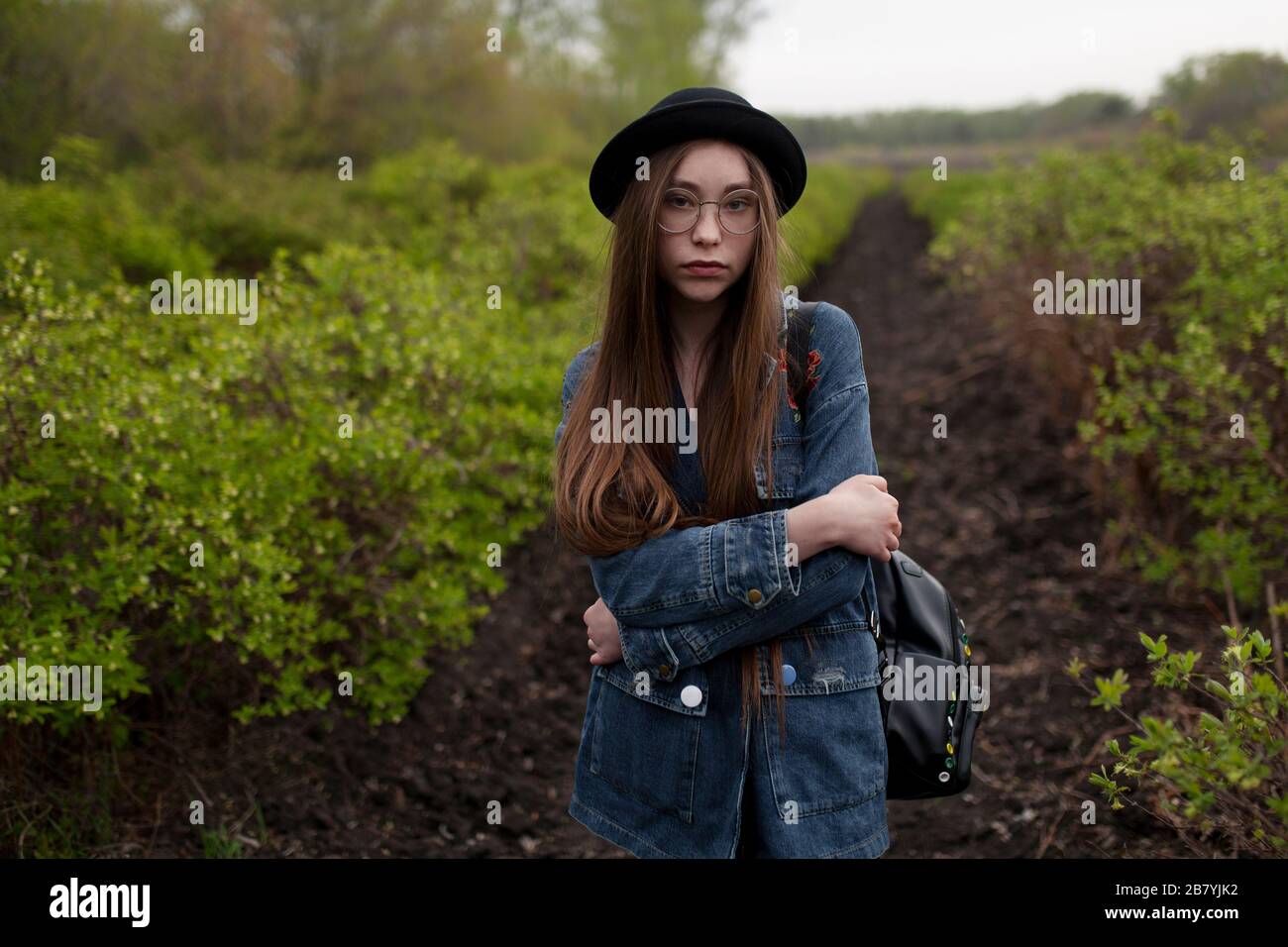 Giovane donna con giacca in denim in piedi sul campo Foto Stock