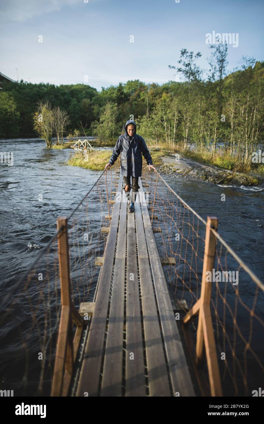 Giovane uomo che cammina sul ponte di legno Foto Stock