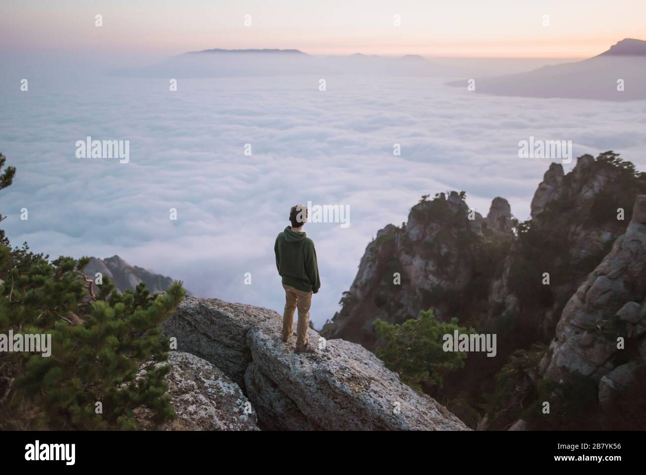 Giovane uomo in piedi sulla montagna sopra la nebbia Foto Stock