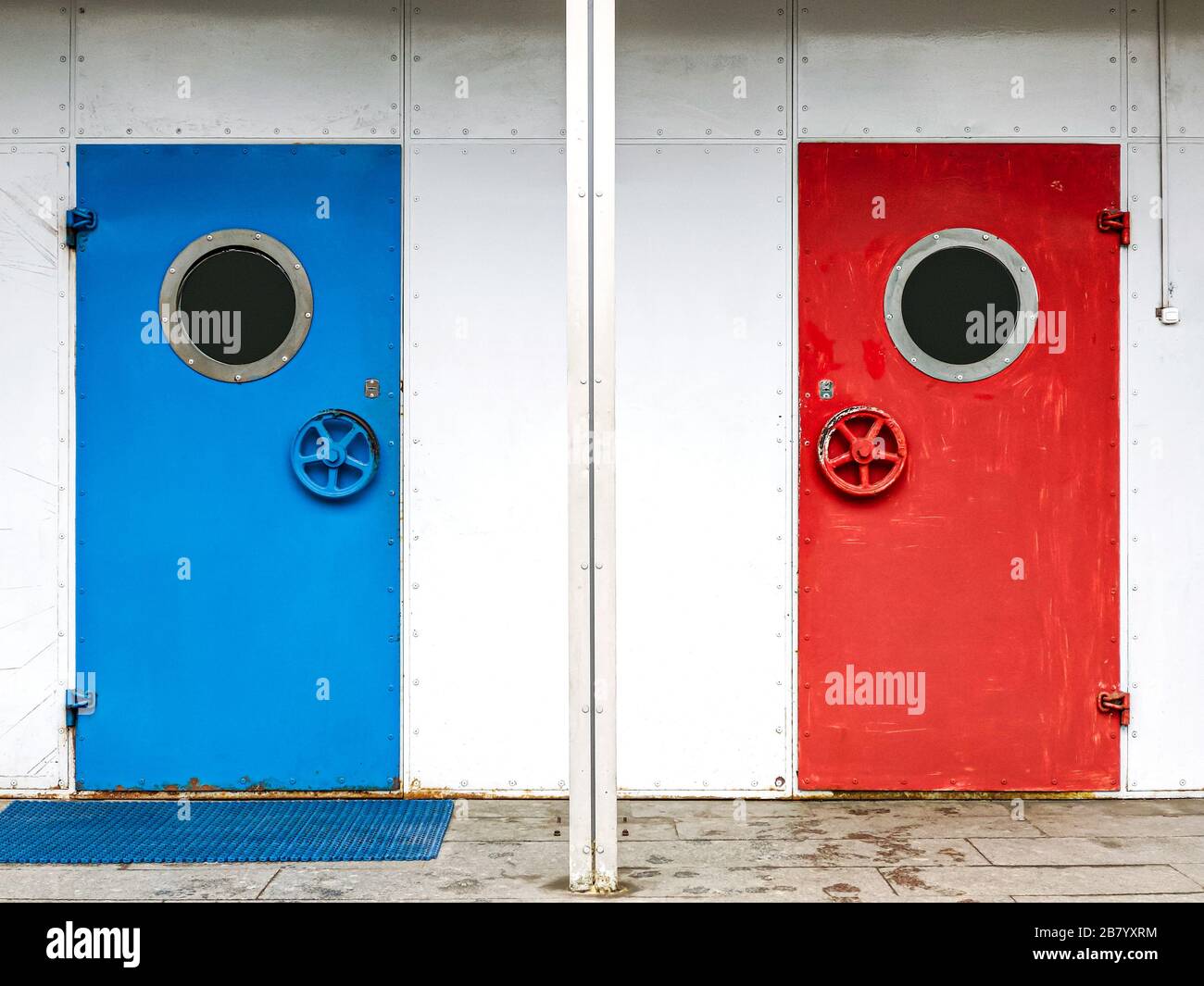 porta dipinta di blu colorato e rosso brillante con oblò. porta d'ingresso in metallo con finestre rotonde Foto Stock