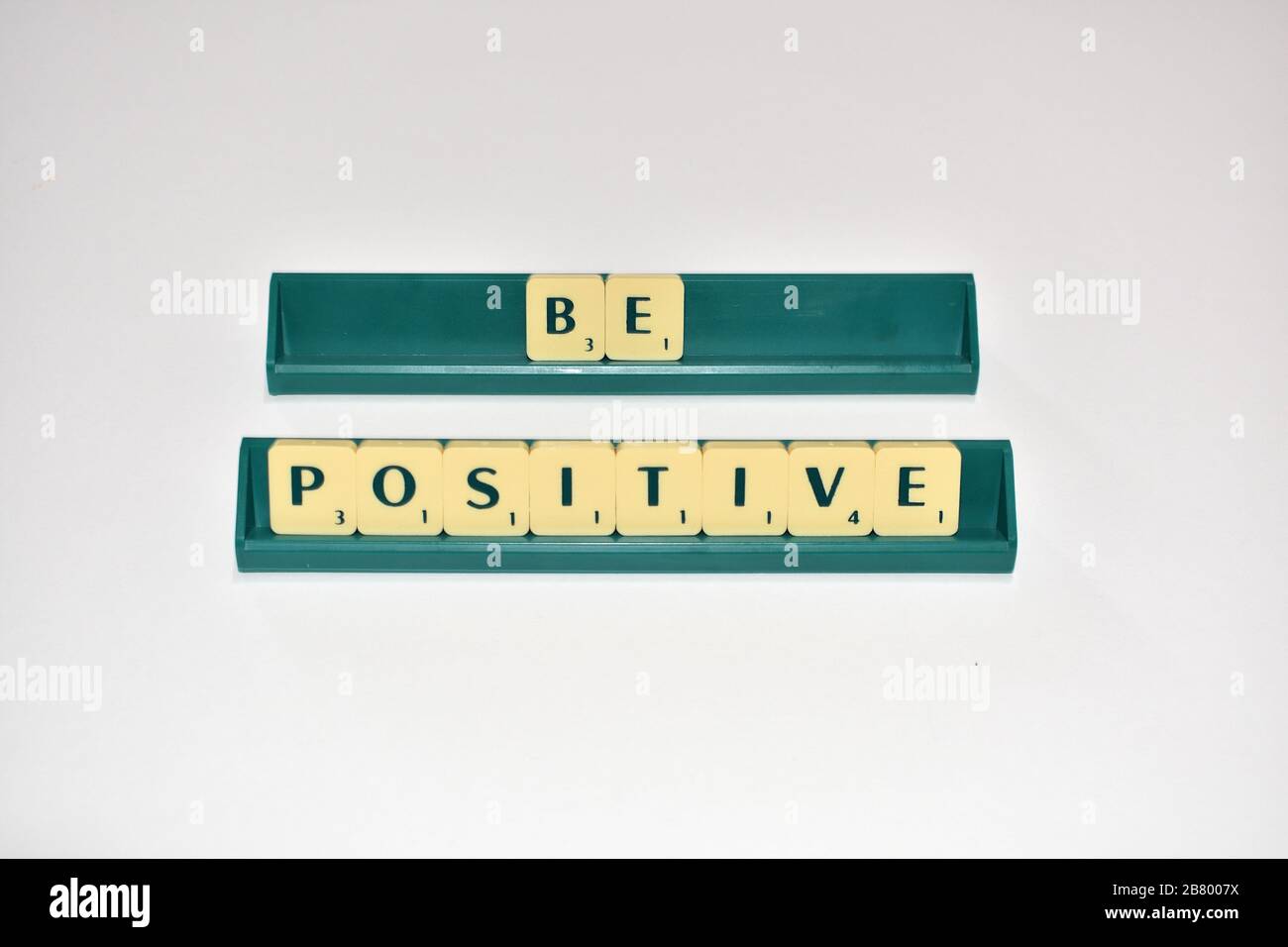 Le tessere Scrabble sono positive. Citazione motivazionale blocchi Scrabble lettere Grigio sfondo citazione di vita indurre alfabeto. Foto Stock