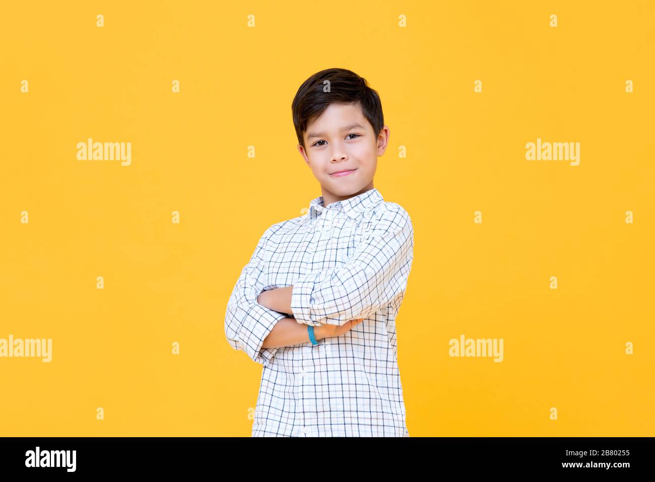 Felice ragazzo sorridente con braccio traversato gesto isolato su sfondo giallo Foto Stock
