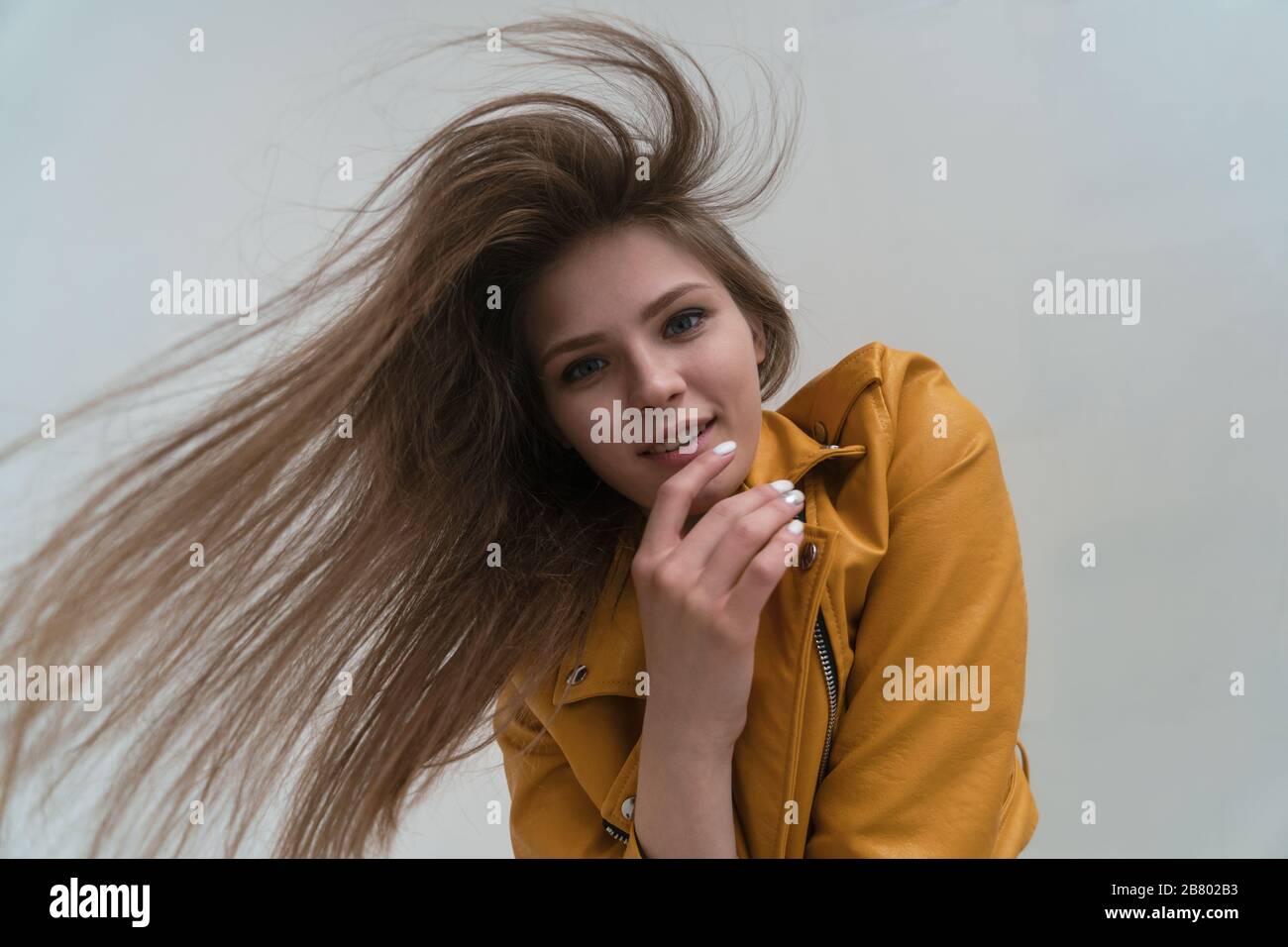 Giovane ragazza dalla pelle discreta con lunghi capelli volanti in posa in studio. Obiettivo grandangolare e guardare la macchina fotografica. Foto Stock